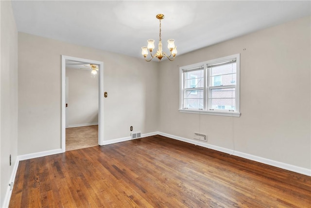 unfurnished room with an inviting chandelier and dark hardwood / wood-style floors