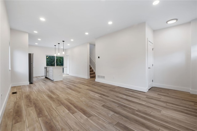 unfurnished living room with sink and light hardwood / wood-style flooring