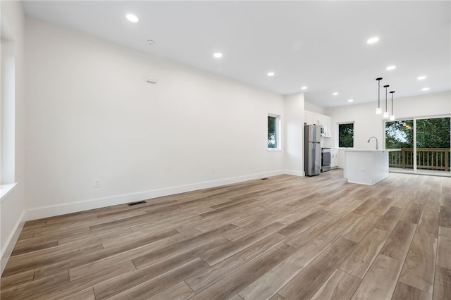 unfurnished living room with sink and light wood-type flooring