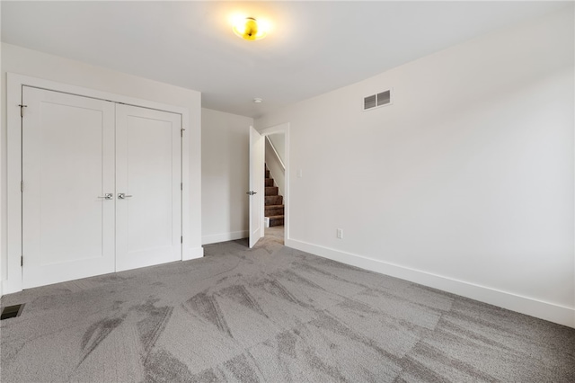 unfurnished bedroom with light colored carpet and a closet