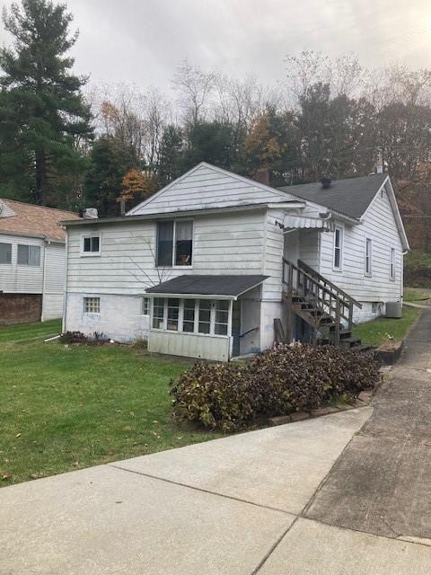 back of property with a sunroom and a lawn