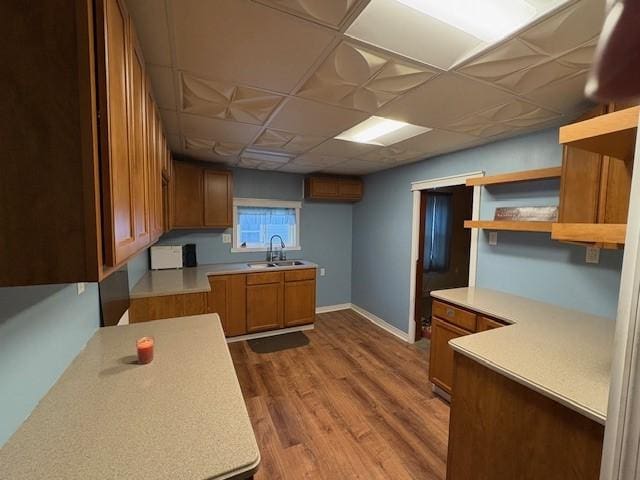 kitchen featuring wood-type flooring, sink, and a drop ceiling