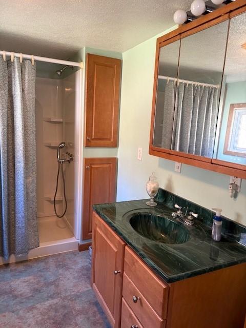 bathroom with vanity, a shower with shower curtain, and a textured ceiling