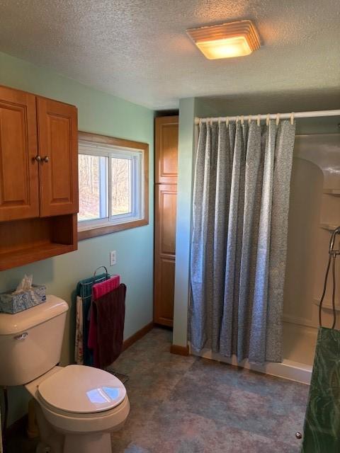 bathroom featuring toilet, curtained shower, and a textured ceiling