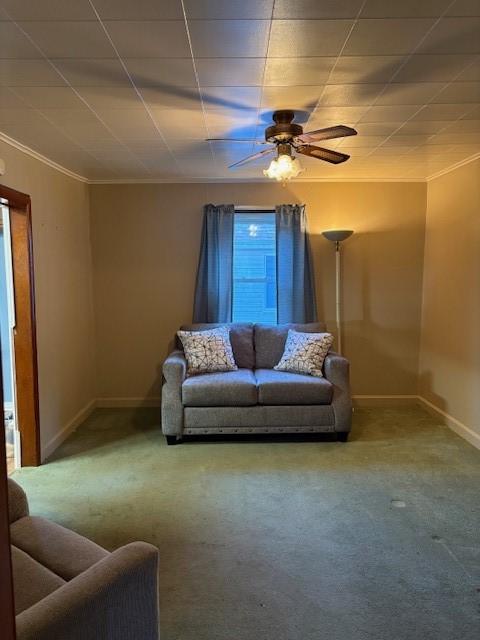 carpeted living room featuring ornamental molding and ceiling fan