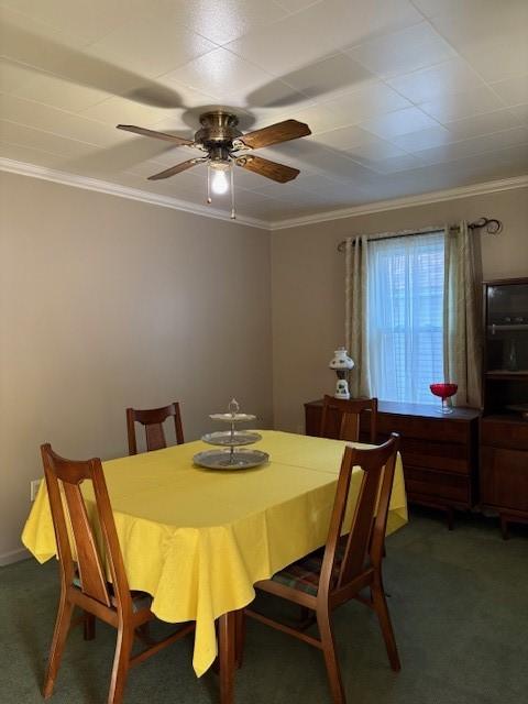 dining area featuring ceiling fan, ornamental molding, and dark colored carpet