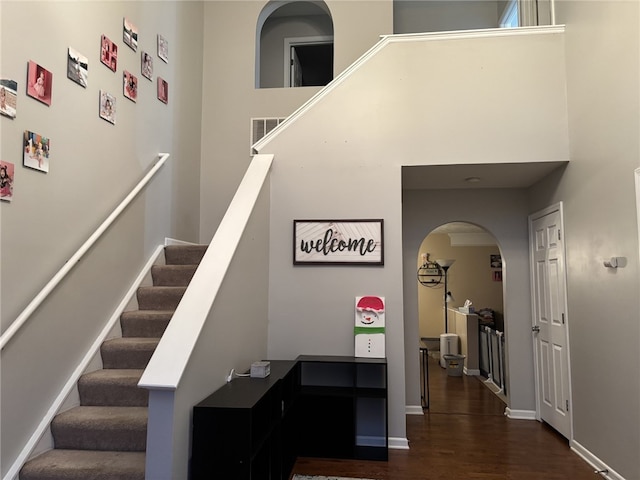 stairs featuring wood-type flooring and a high ceiling