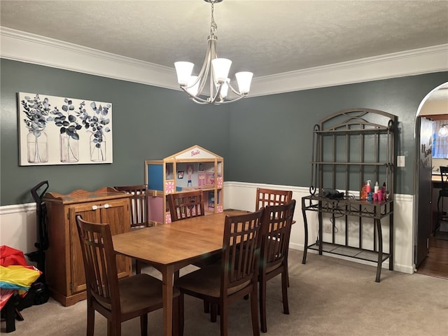 dining room featuring an inviting chandelier, crown molding, carpet floors, and a textured ceiling