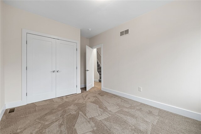 unfurnished bedroom featuring light colored carpet and a closet
