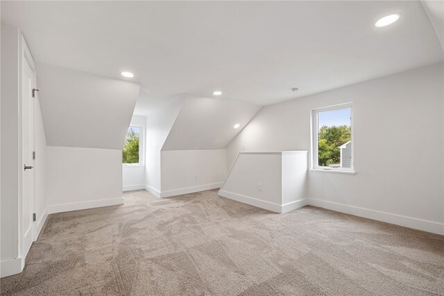 bonus room with vaulted ceiling and light colored carpet