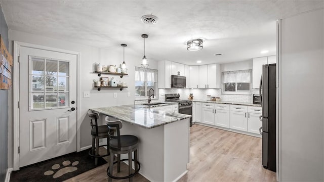 kitchen with stone countertops, stainless steel appliances, white cabinets, a kitchen bar, and kitchen peninsula