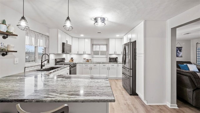 kitchen featuring sink, white cabinetry, dark stone countertops, stainless steel appliances, and kitchen peninsula