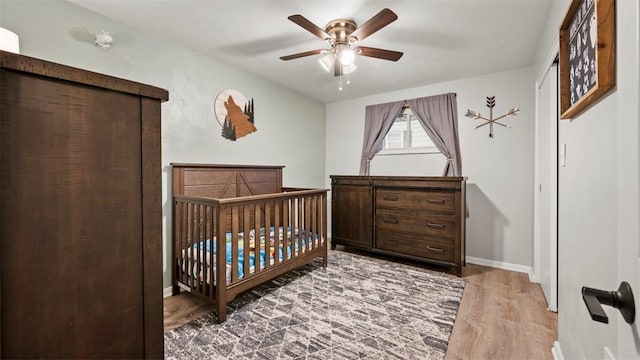 bedroom featuring hardwood / wood-style flooring, a nursery area, and ceiling fan