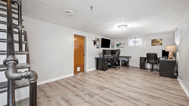 home office featuring light hardwood / wood-style floors and a textured ceiling