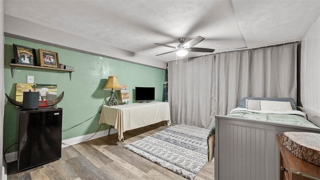 bedroom with ceiling fan, hardwood / wood-style floors, and a textured ceiling