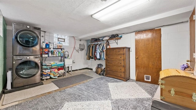 clothes washing area featuring stacked washer / drying machine, sink, and a textured ceiling