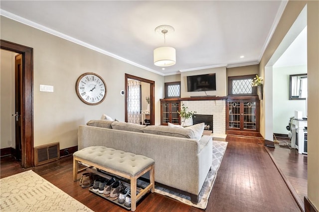 living room with ornamental molding, a brick fireplace, and dark hardwood / wood-style flooring