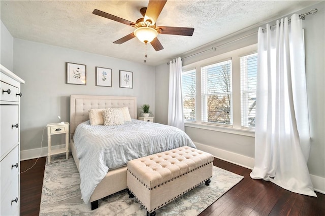 bedroom with ceiling fan, dark wood-type flooring, and a textured ceiling