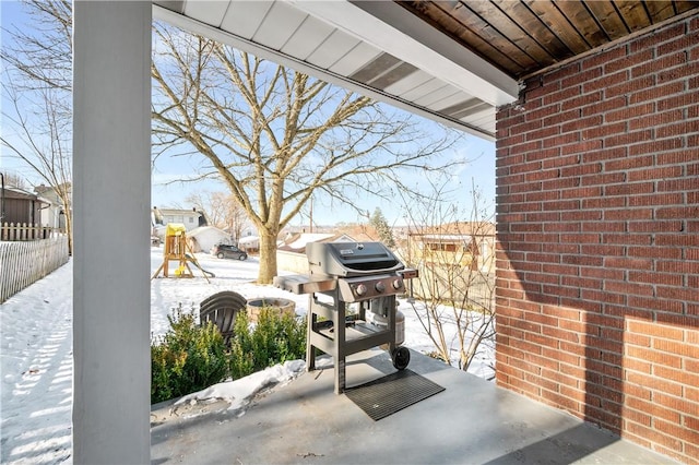 snow covered patio featuring a playground and area for grilling