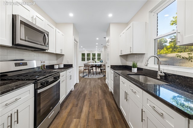 kitchen with sink, stainless steel appliances, dark stone counters, and white cabinets