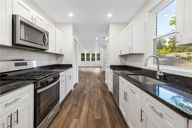 kitchen with dark stone countertops, stainless steel appliances, sink, and white cabinets