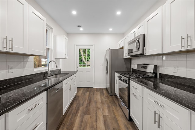 kitchen featuring appliances with stainless steel finishes, sink, dark stone counters, and white cabinets