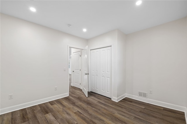 unfurnished bedroom with dark hardwood / wood-style floors and a closet