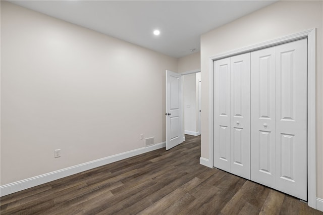 unfurnished bedroom with dark wood-type flooring and a closet