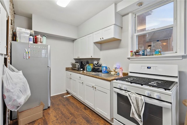 kitchen with sink, stainless steel fridge, white gas stove, and white cabinets