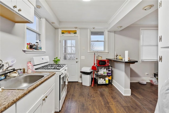 kitchen featuring sink, white cabinets, white gas range oven, light stone countertops, and dark wood-type flooring