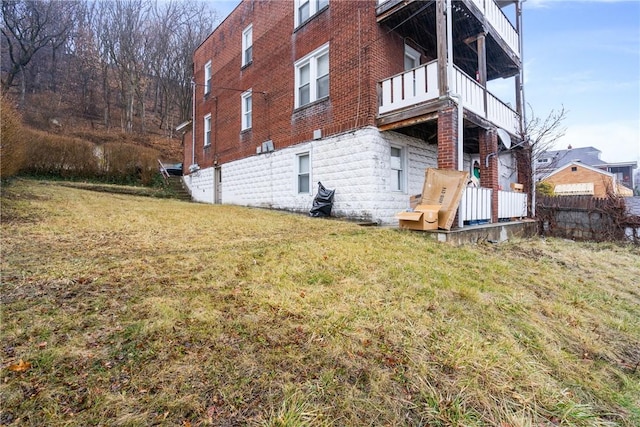 view of property exterior featuring a balcony and a lawn