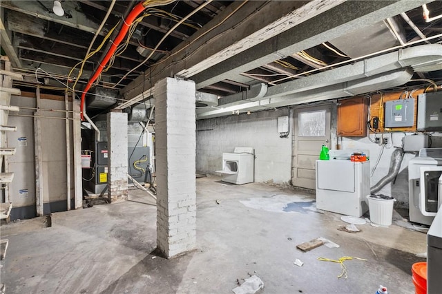 basement featuring heating unit, electric panel, and washer and dryer