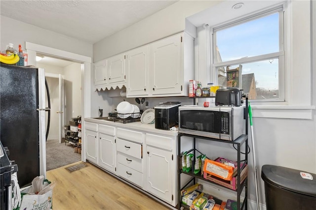 kitchen featuring stainless steel appliances, light hardwood / wood-style floors, and white cabinets