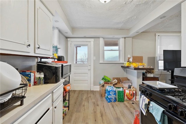 kitchen featuring white cabinetry, black gas range oven, a textured ceiling, and light wood-type flooring