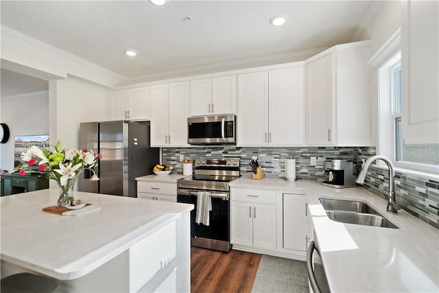 kitchen featuring sink, backsplash, stainless steel appliances, ornamental molding, and white cabinets