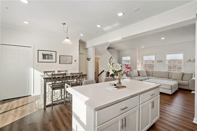 kitchen featuring white cabinetry, decorative light fixtures, dark hardwood / wood-style floors, and a center island