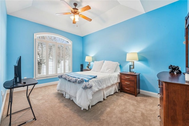 bedroom featuring ceiling fan, a tray ceiling, vaulted ceiling, and light carpet