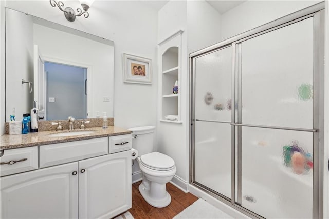 bathroom with hardwood / wood-style flooring, vanity, toilet, and a shower with door