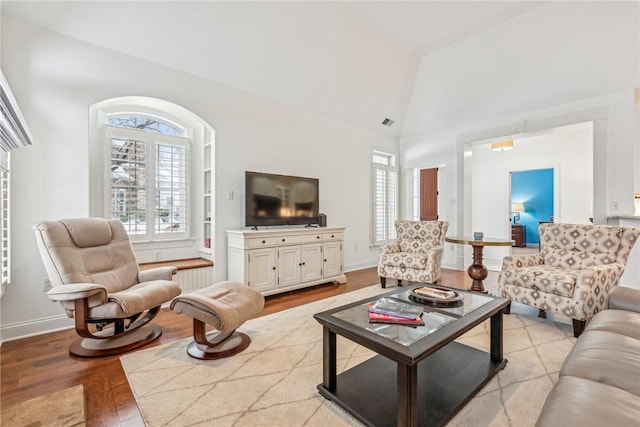 living room with high vaulted ceiling and light hardwood / wood-style floors