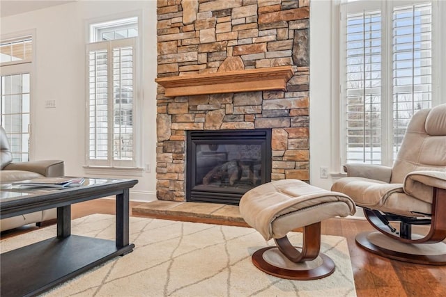 living area featuring a stone fireplace, plenty of natural light, and hardwood / wood-style floors