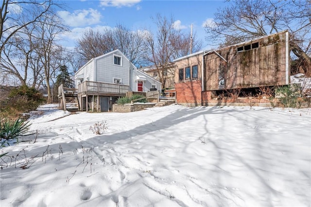 snow covered back of property featuring a wooden deck