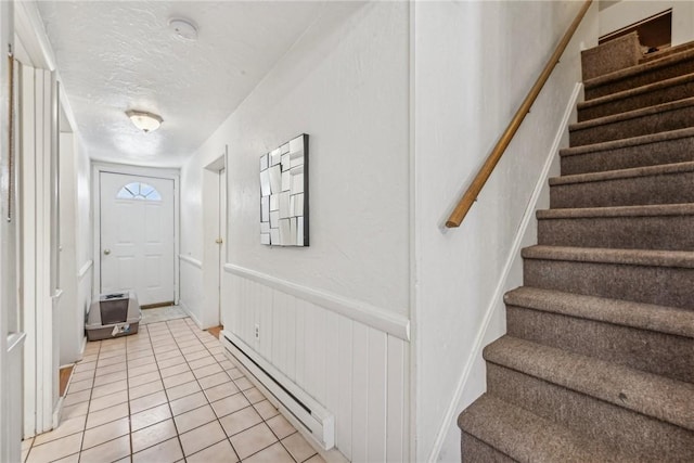 entryway with a baseboard radiator, light tile patterned floors, and a textured ceiling