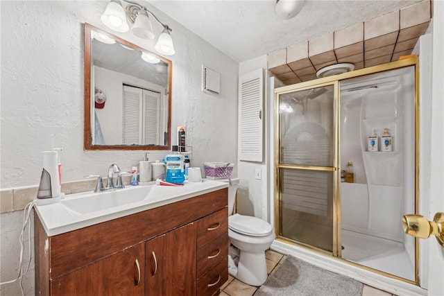 bathroom with vanity, a shower with shower door, tile patterned floors, and toilet