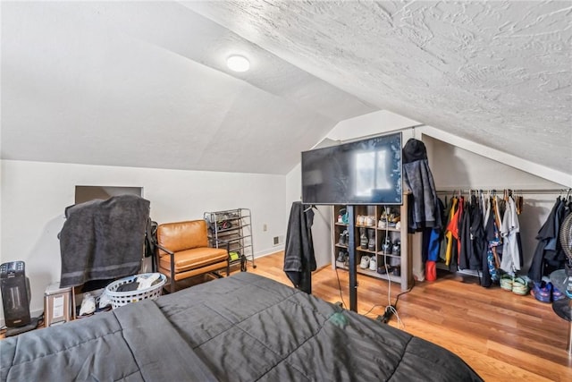 bedroom with hardwood / wood-style flooring, lofted ceiling, and a textured ceiling