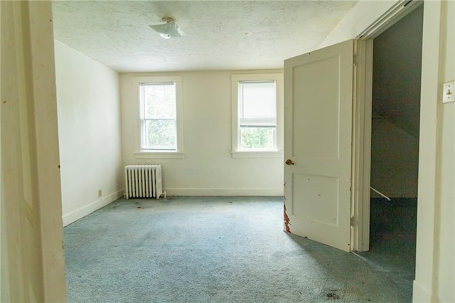 carpeted spare room featuring radiator heating unit and a textured ceiling