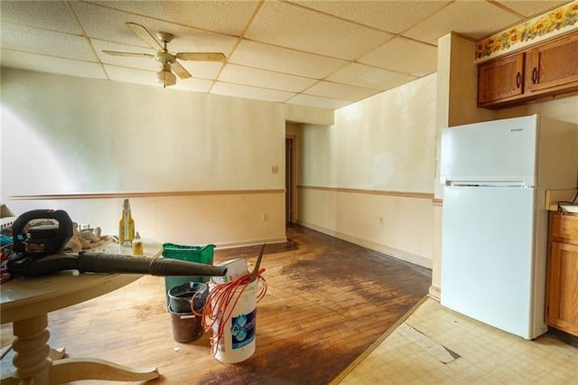 interior space with white fridge, a drop ceiling, and ceiling fan