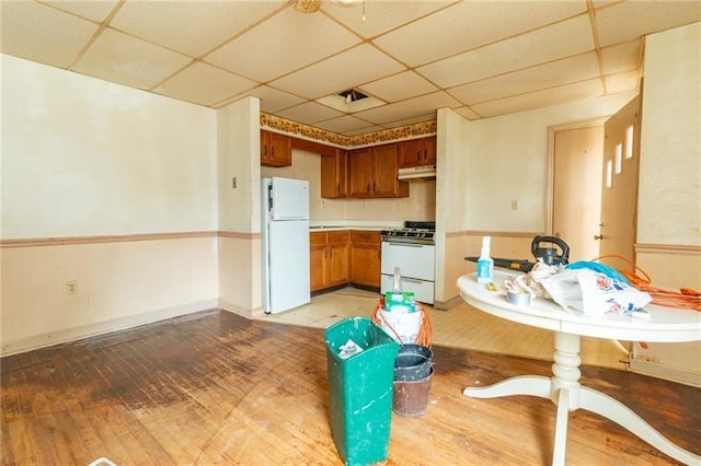 kitchen featuring a paneled ceiling, white appliances, and light hardwood / wood-style floors