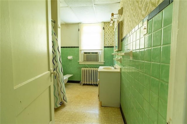 bathroom with radiator, cooling unit, tile walls, vanity, and toilet