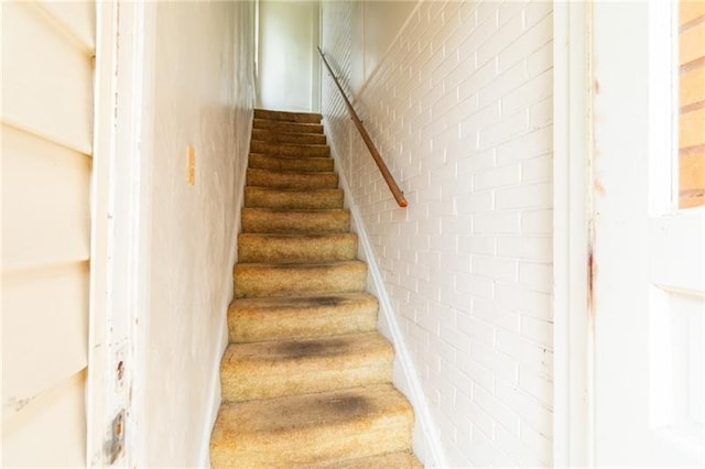 stairway featuring brick wall