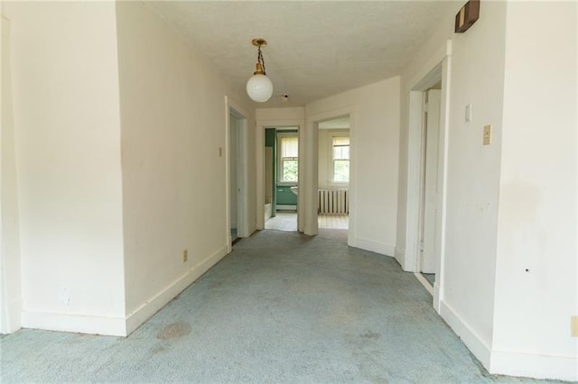 hallway with radiator and light colored carpet